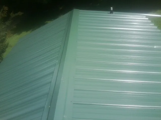 New green metal panels meeting at the ridge of a roof — Flat Roof Repair work by our crew in Lehigh