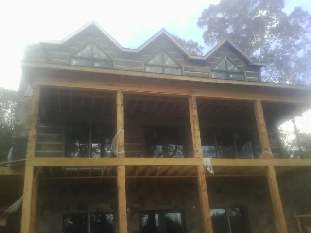 Dormers and porch framing on a large log home under construction — Roof Coating work by our crew in Lehigh